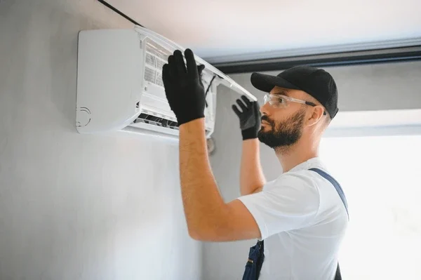 Technician securing AC pipes and wiring during installation